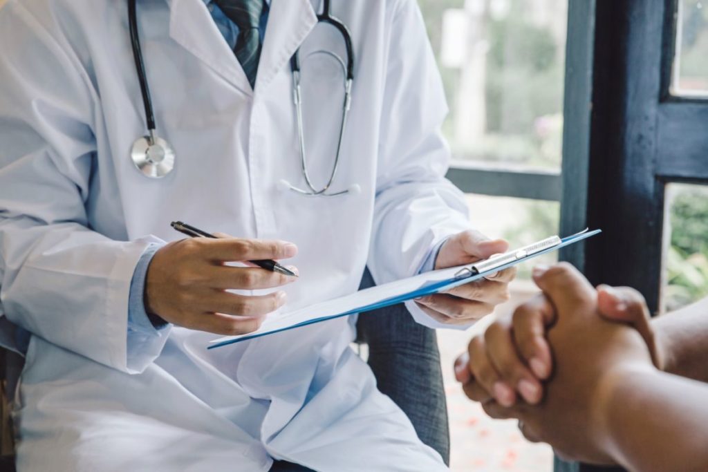 Doctor writing notes during a consultation about hormone therapy